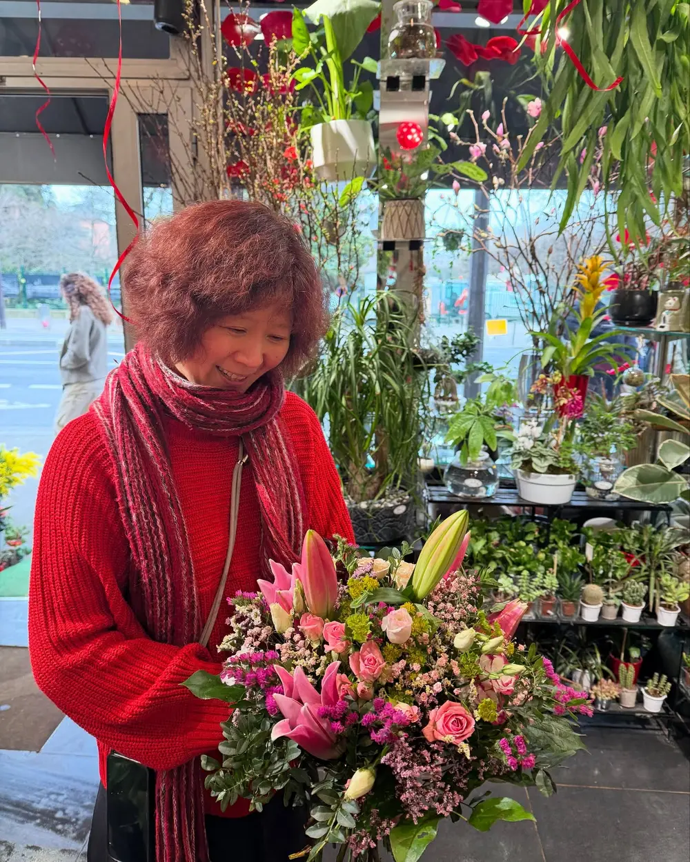 Ava dans sa boutique, tenant un bouquet de lys et de roses