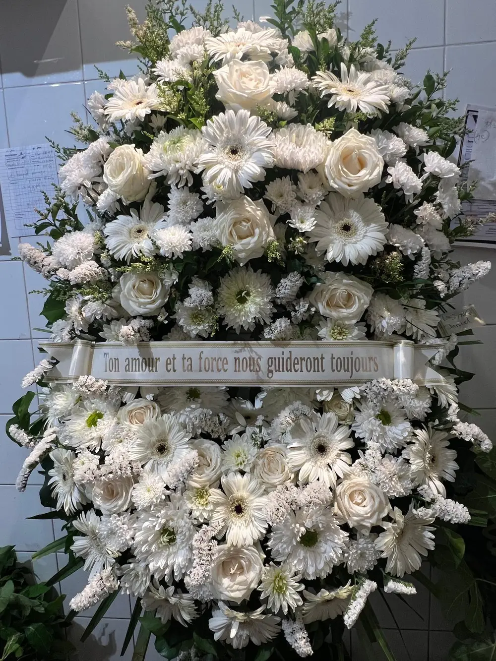 Grande composition de deuil en fleurs blanches, roses et chrysanthèmes, avec un ruban de message